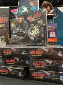 A photo of stacked boxes of War Story: Occupied France for sale at Gen Con 2024