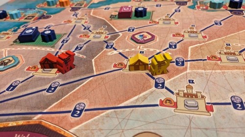 A close-up of the Astronomy area of the bard, depicting a map of North Africa with various trade routes connecting settlements, and wooden tokens depicting tents, camels and books placed around it