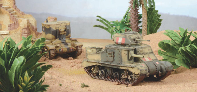 A photo of fully painted miniature figures and terrain for wargaming: two tanks rolling through a desert oasis