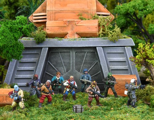 A photo of fully painted miniature figures and terrain for wargaming: a heavily armed crew of humans and aliens stand in front of a strange ruin surrounded by green jungle.