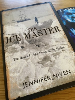 A photo of the book The Ice Master: The Doomed 1913 Voyage of the Karluk by Jennifer Niven, with a cover depicting a sailed ship in the distance off a bank off ice where a lone figure stands