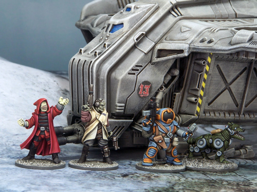 A photo of miniature figures and terrain for wargaming: a crew of aliens and a robot dog in front of their landed spaceship in a snowy environment.