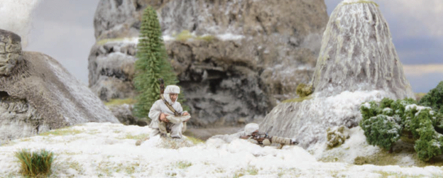 A photo of fully painted miniature figures and terrain for wargaming: two WW2 snipers taking cover in snow