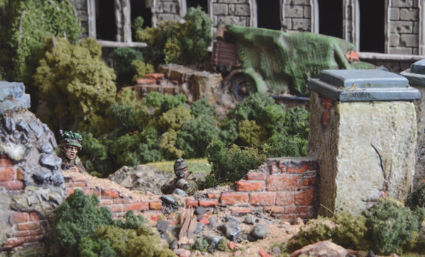 An image of fully painted miniature figures and terrain for wargaming depicting two WW2 snipers taking cover and aiming from behind a ruined wall