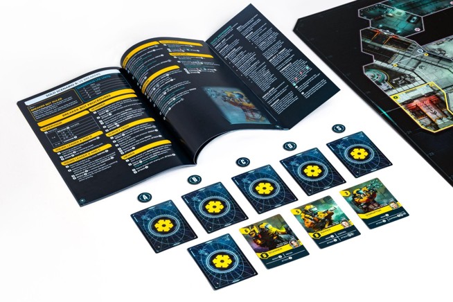 A photo of an open spread from the Callisto solo rulebook above an array of cards and tokens set up next to a board for solo play