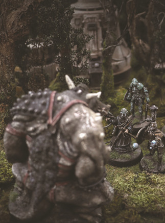 A photo of fully painted miniatures against overgrown ruined terrain: a huge monster is faced away and towering over three high-tech, knight-like figures