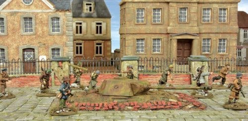 A photo of fully painted miniature figures and terrain for wargaming depicting a squad of German WW2 engineers in a town around a turret emplacement