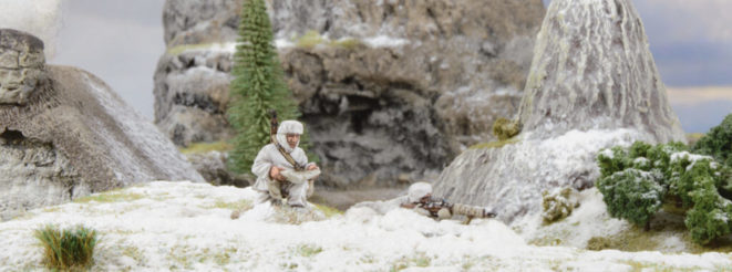 A photo of fully painted miniature figures and terrain for the WW2 wargame Bolt Action: camouflaged snipers scanning the horizon from a snowy hill