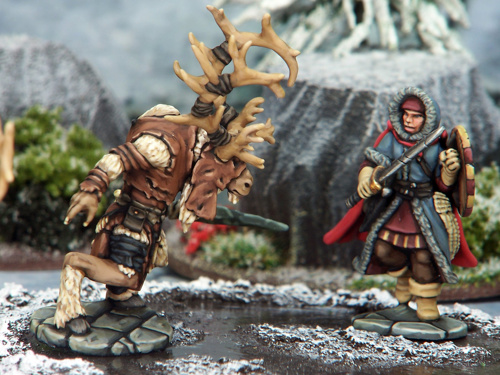 A photo of fully painted miniature figures of a reindeer-like humanoid and a warrior dressed in furs, against a snowy mountainous backdrop.